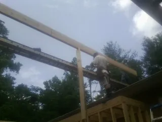 Carpenter setting a ridge beam over a new addition frame — Ice Dam Removal by Roofing Brothers in Lapine