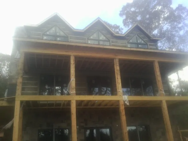 Dormers and porch framing on a large log home under construction — Roof Coating work by our crew in Lapine