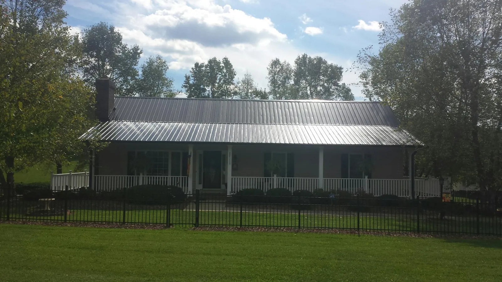 Gray metal roof on a brick ranch with a full width front porch — Gutter Guard Installation work by our crew in Lapine