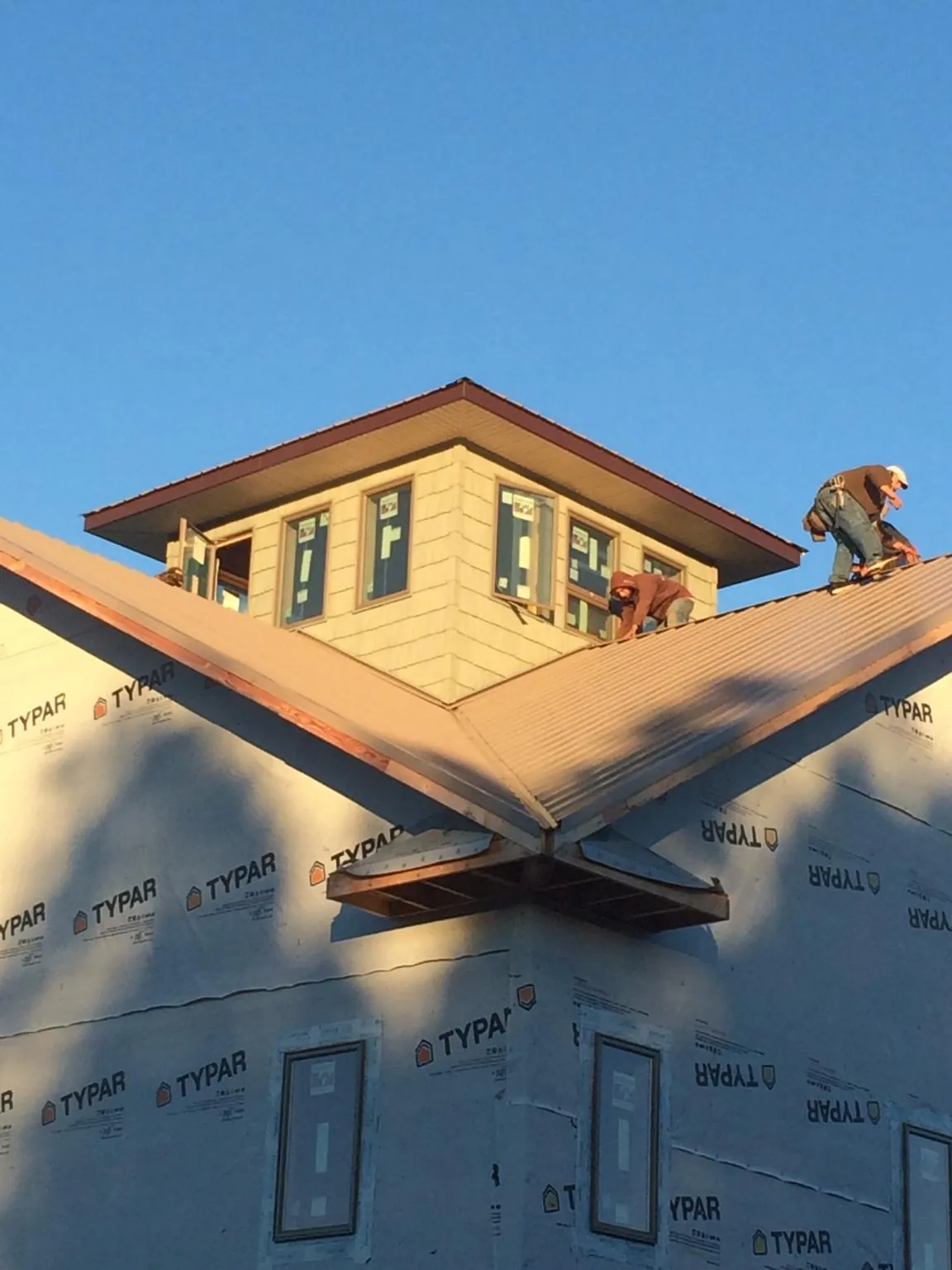 Roofers working around a rooftop cupola on a new metal roof at sunset — Roof Waterproofing in Lapine by Roofing Brothers